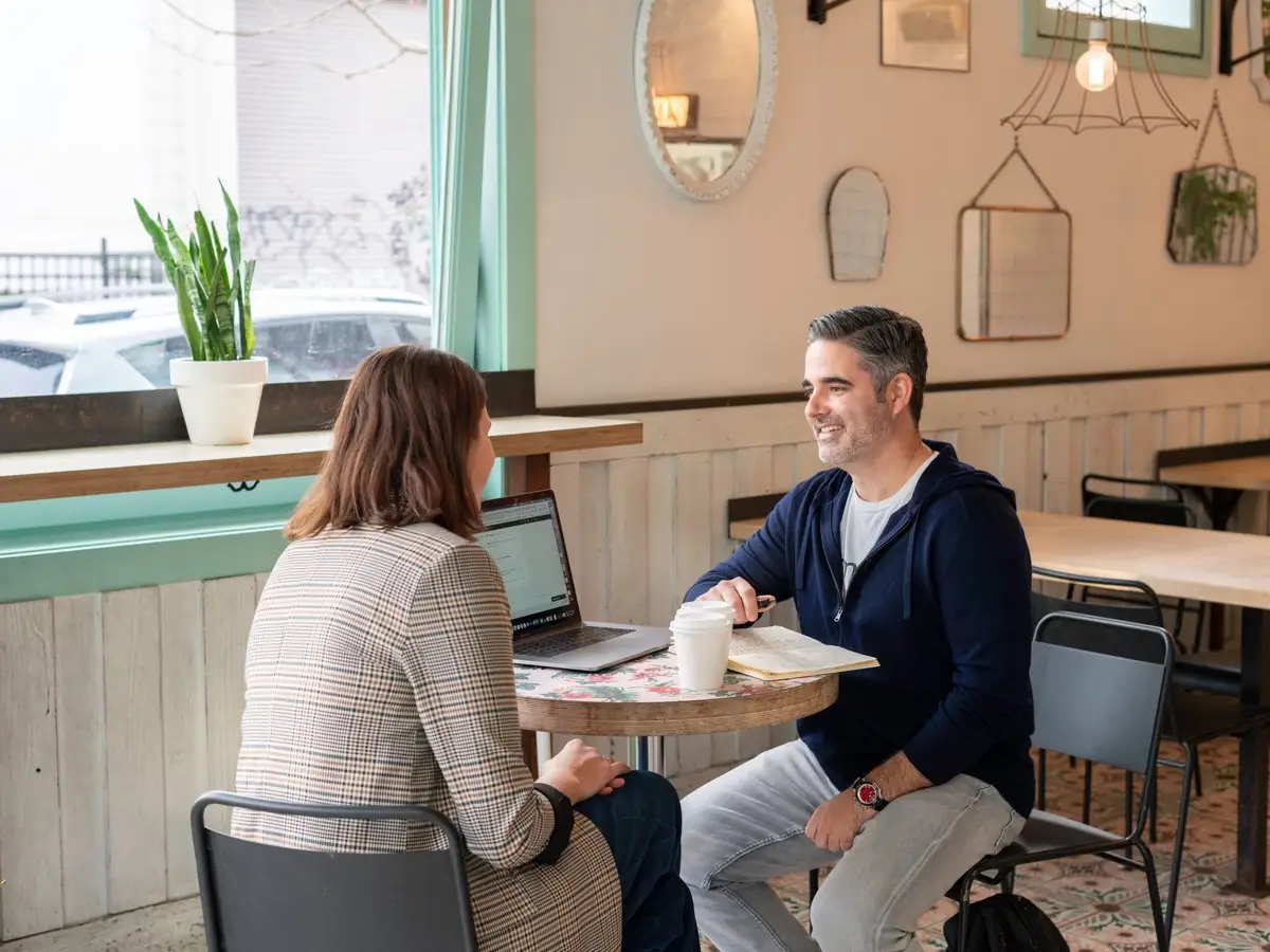 Zwei Personen im ruhigen Beratungsgespräch an einem Cafétisch
